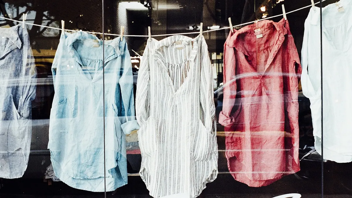Camisas claras penduradas em varal diante de janela