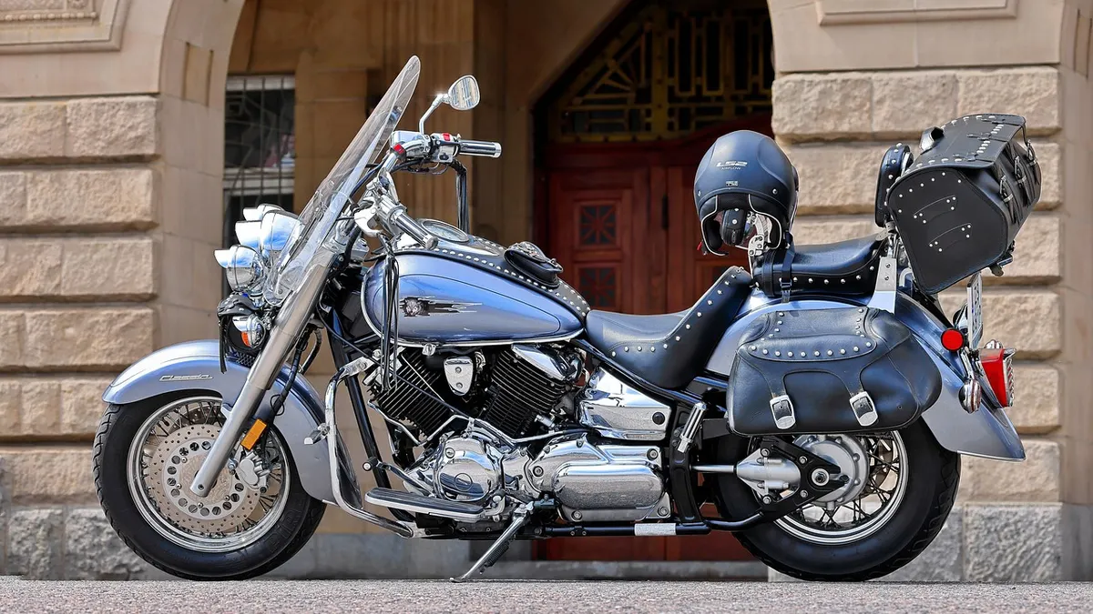 Moto custom prata estacionada diante de prédio de pedra